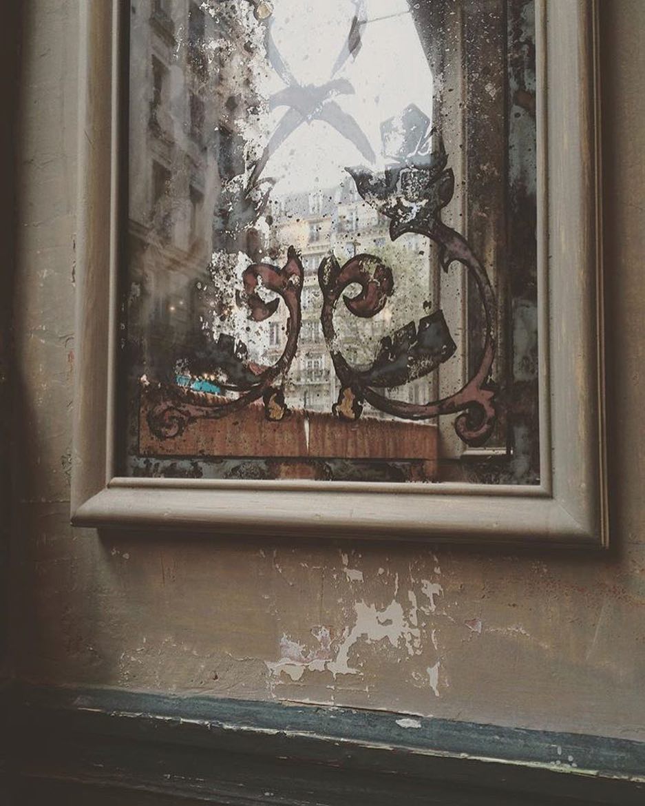 Miroir ancien piqué et gravé reflétant les immeubles haussmanniens de la rue