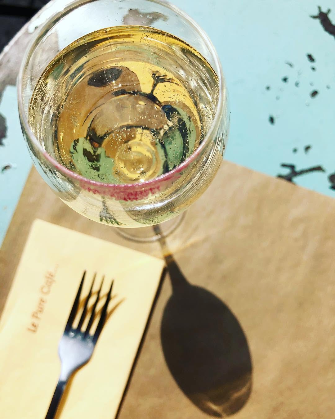 Coupe de vin blanc pétillant posée sur une serviette du Pure Café en terrasse