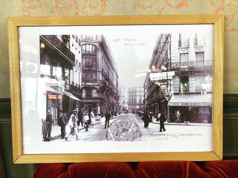 Carte postale ancienne encadrée de la rue Jean-Macé, posée sur la banquette rouge